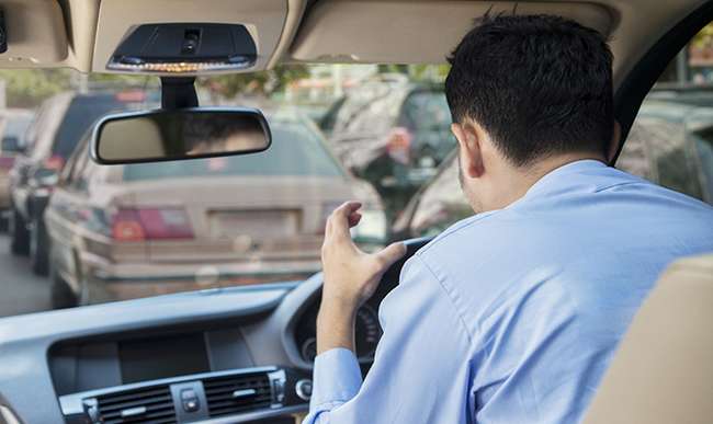 Rear view of furious young man driving a car on the road at the traffic jam